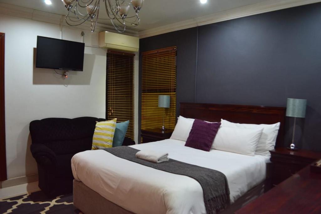 A guest room with a double bed, sofa, television and chandelier