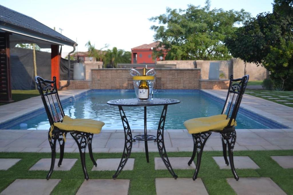 A table for two set beside the hotel pool at dusk, with a bottle on ice