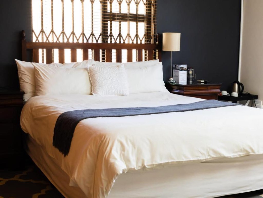 A made king bed against a navy wall with a coffee station